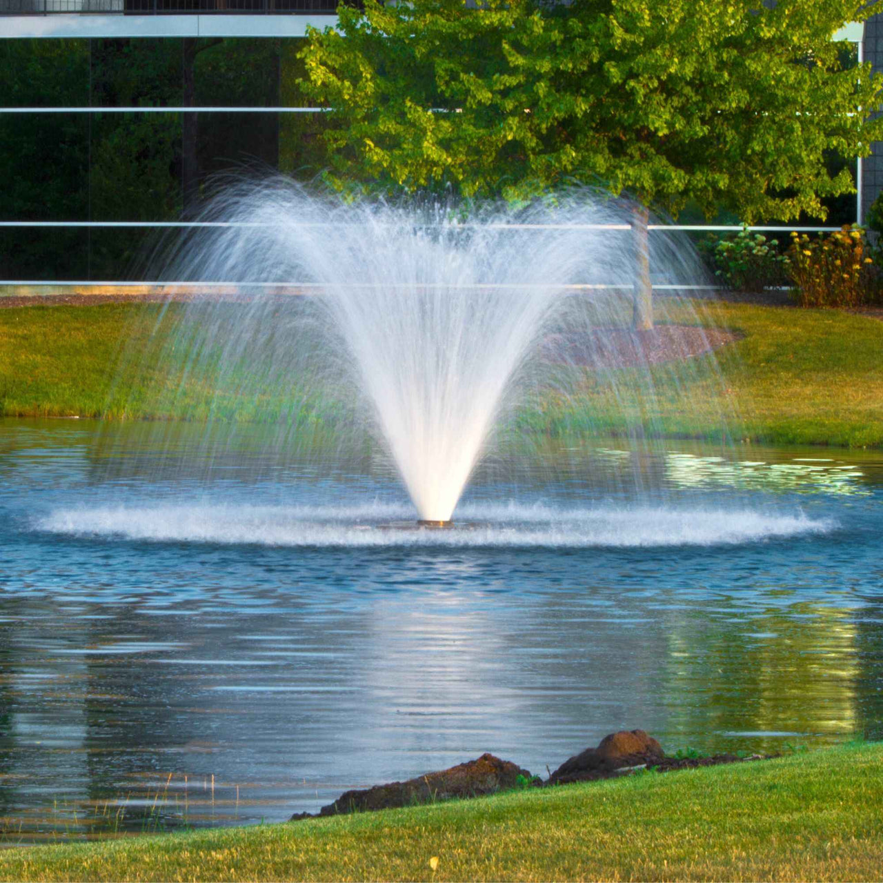 Scott Aerator DA-20 Display Pond Aerator Fountain On Blue Water With A Green Tree In The Background