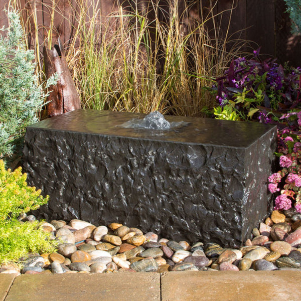 Shizukesa Stone Outdoor Fountain Surrounded By Colorful Plants And Flowers