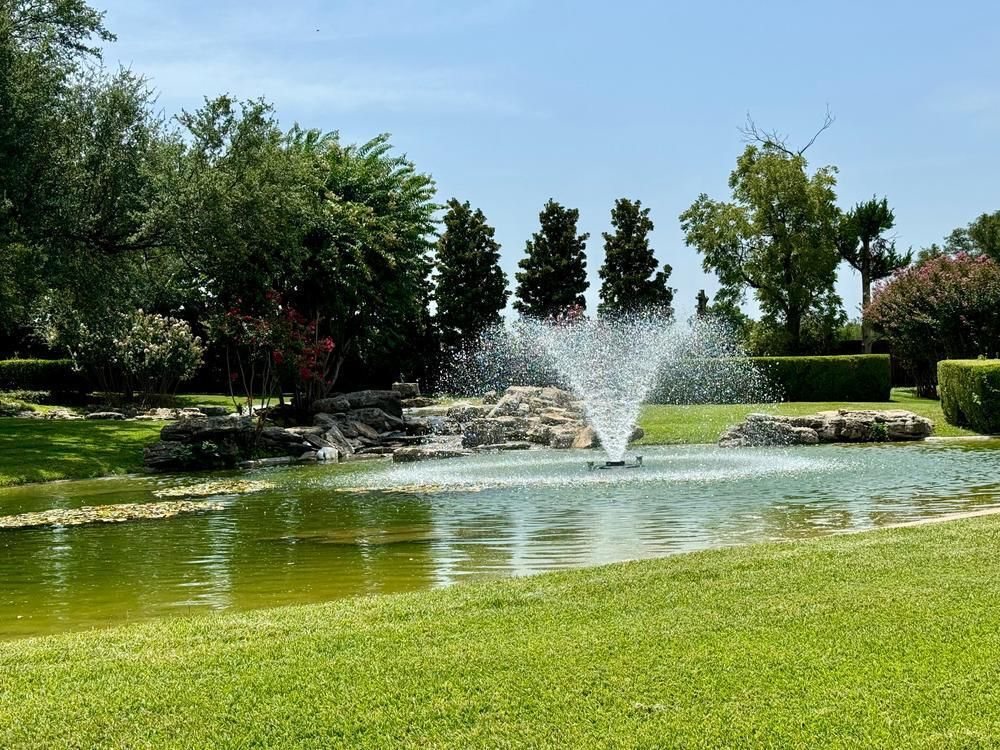 Customer pond with a fountain, rock edging and mature trees