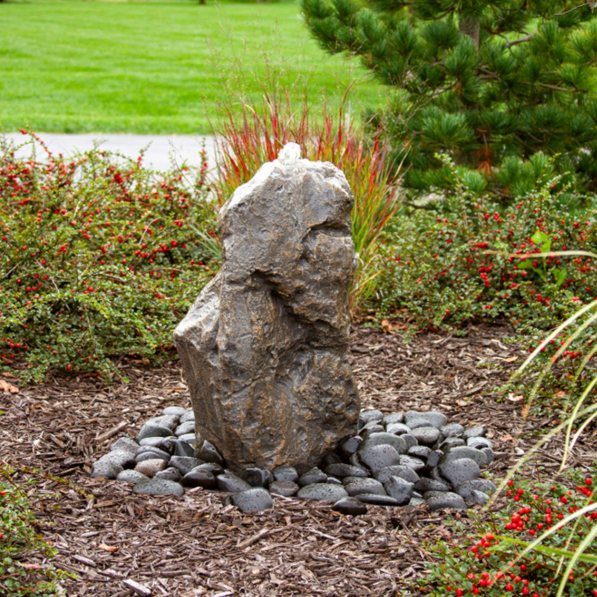 Blue Thumb Sonoma rock fountain running in a garden bed surrounded by flowering plants and trees