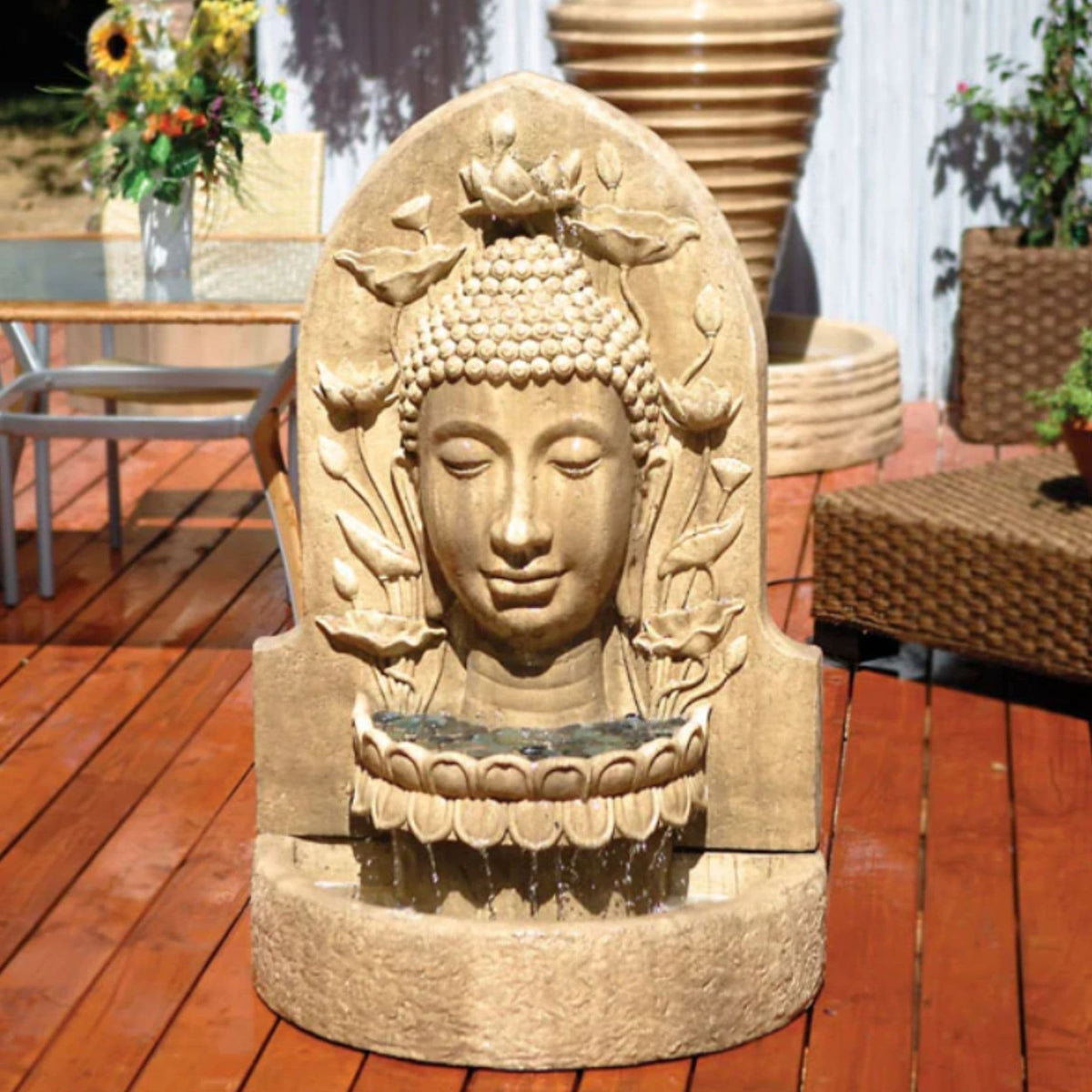 GIST Buddha wall garden fountain with a carved stone face spilling water into a basin on a timber deck