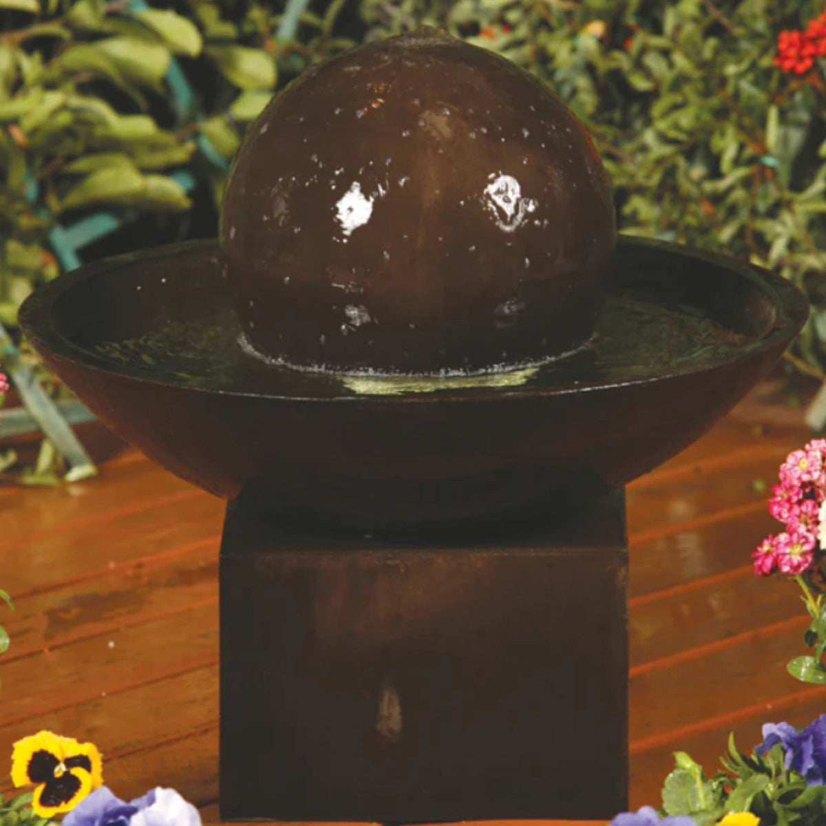 GIST small wok bowl fountain raised on a pedestal with water brimming over the rim, ringed by plants and flowers