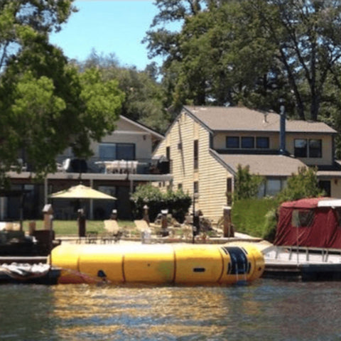 20 Acrobat Water Trampoline Floating In Calm Water And Houses In The Background