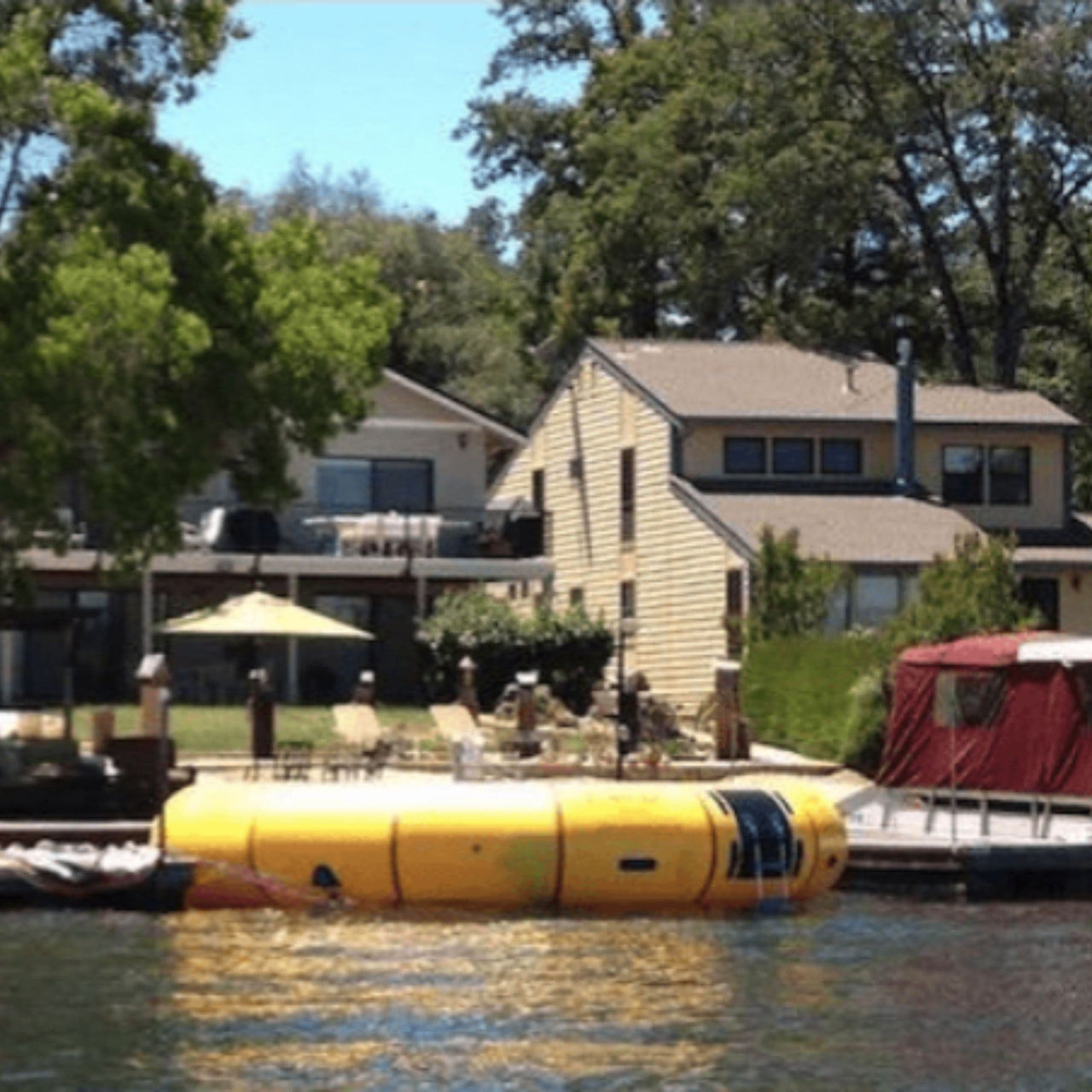 20 Acrobat Water Trampoline Floating In Calm Water And Houses In The Background