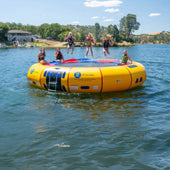 20 Island Hopper Water Trampoline Three Girls Are Jumping While The Other Three Are Sitting With A House And Scenic View