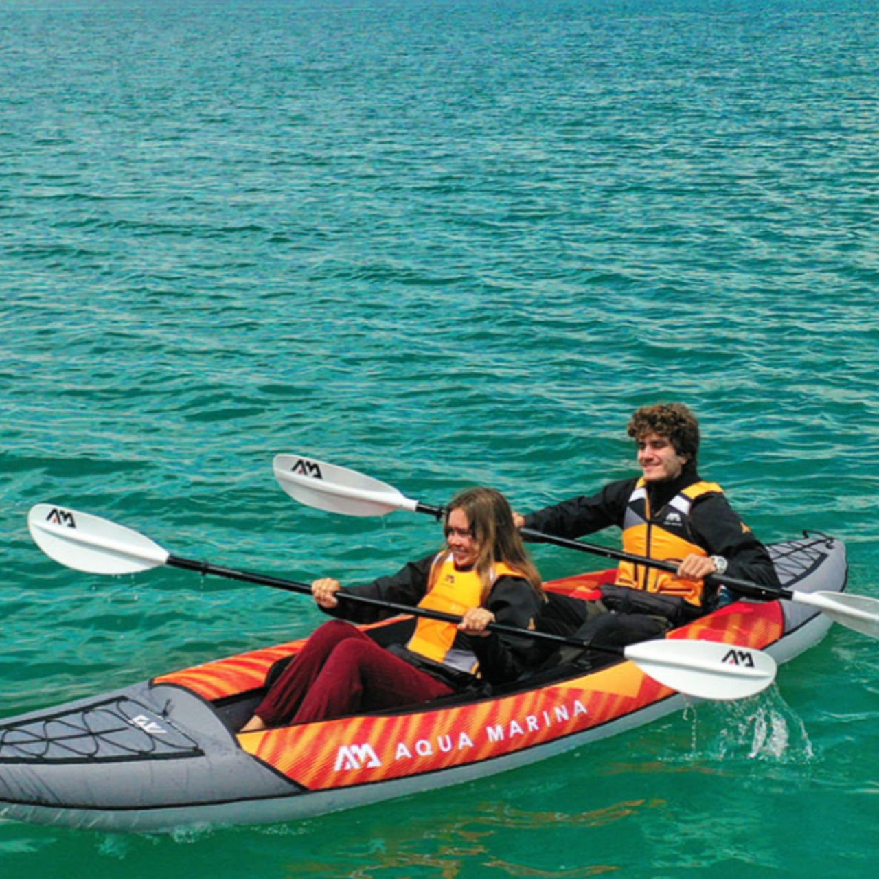 Aqua Marina Memba Kayak With A Man And A Woman Kayaking And Paddling Across The Calm Water