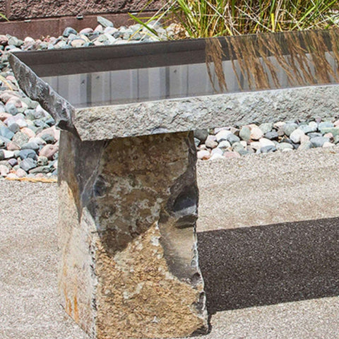 Basalt 48 Garden Bench Close-up View With Red Brick Wall And Garden Grass In The Background