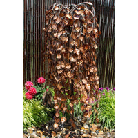 Thumbnail for Blue Thumb 60 Copper Weeping Elm Tree Garden Fountain Surrounded By Flowers And Green Plants With Wooden Fence In The Back