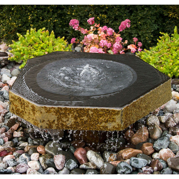 Blue Thumb Basalt Bird Bath Stone Fountain With Green Plants And Flowers Behind
