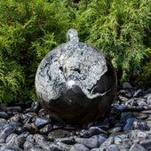 Blue Thumb Black Flower Granite Stone Sphere Fountain With Flowing Water And Plants Behind