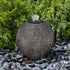Thumbnail for Blue Thumb Black Ribbed Granite Sphere Fountain With Bushes In The Background