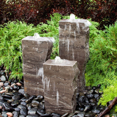 Blue Thumb Blue Limestone Triple Rock Fountain with 3 Smooth Sides With Bushes In The Background