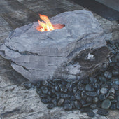 Blue Thumb Boulder Outdoor Fire Stone Fountain With A Fire And Surrounded by Black Pebbles