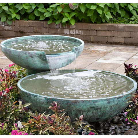 Blue Thumb Double Spillway Stone Bowl Fountain Surrounded By Plants And Bricks In The Background