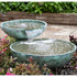 Thumbnail for Blue Thumb Double Spillway Stone Bowl Fountain Surrounded By Plants And Bricks In The Background