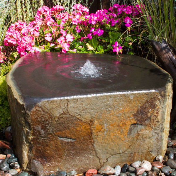 Blue Thumb Keki Stone Outdoor Fountain Beside Grass And Pink Flowers