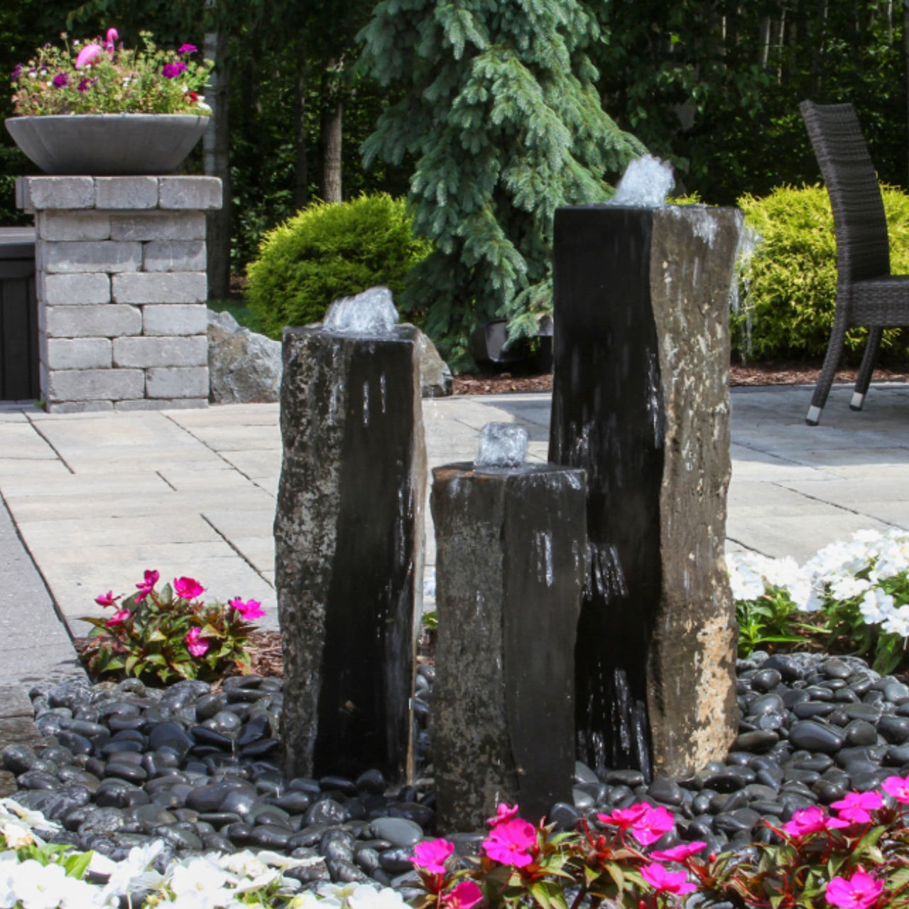 Blue Thumb One Side Polished Basalt Stone Fountain Surrounded By Flowers With Chair And Trees Behind