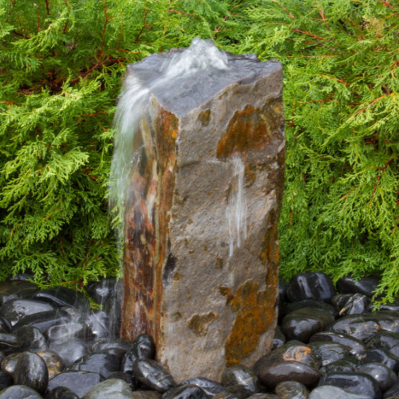 Blue Thumb Rustic Basalt Column Fountain With Shrubs Behind