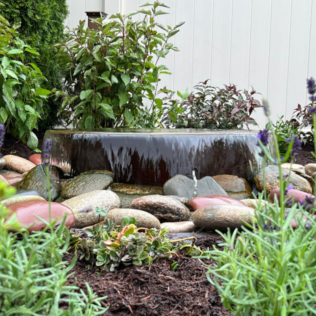 Blue Thumb Rustic Sugar Kettle Powder-Coated Cast Iron Fountain Surrounded By Ornamental Plants