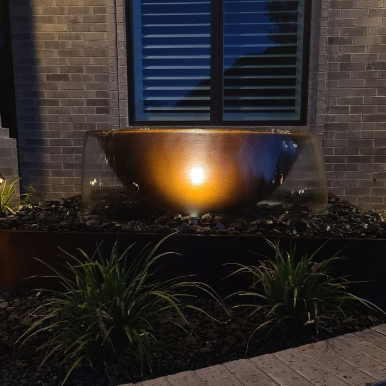Blue Thumb Rustic Sugar Kettle Powder-Coated Cast Iron Fountain With Light Accent And Brick Wall Behind