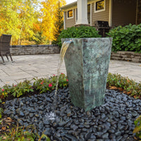 Thumbnail for Blue Thumb Single Tapered Square Urn Stone Fountain Surrounded By Flowers With Modern House And Trees Background