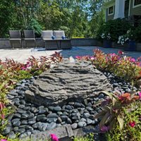 Thumbnail for Blue Thumb Slate River Falls Stone Fountain Surrounded By Plants With Modern House And Chairs Background