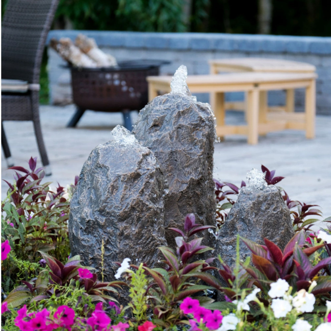 Blue Thumb Triple Matterhorn Outdoor Fountain Rock Surrounded By Flowers With Chairs Background