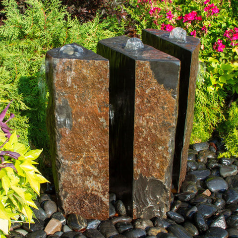 Blue Thumb Triple Split Polished Basalt Stone Outdoor Fountain With Rich Green Shrubs In The Back