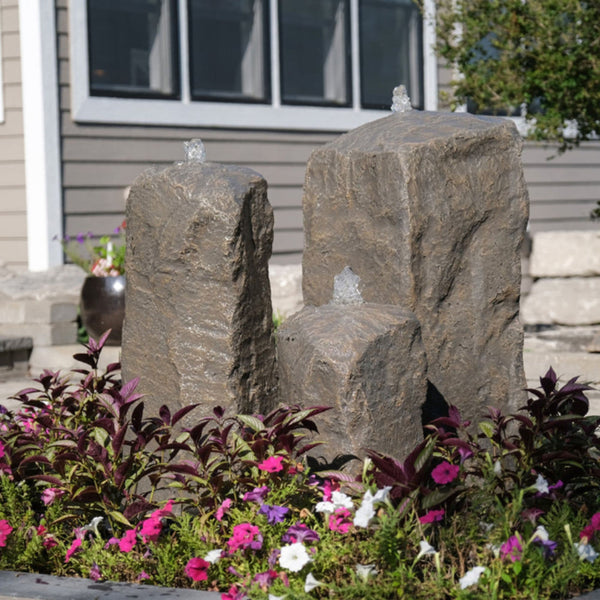 Blue Thumb Watershed Cascade Triple Stone Outdoor Fountain Surrounded By Colorful Flowers With Modern House In The Background