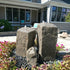 Thumbnail for Blue Thumb Watershed Tall Double Rock Outdoor Fountain Surrounded By Colorful Plants With A Modern House In The Background