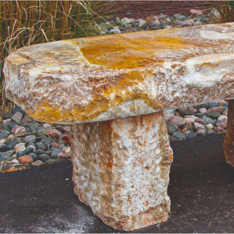 Blue Thumb Yellow Onyx Garden Bench Close-up View Near Brown Wall With Pebbles And Tall Grasses