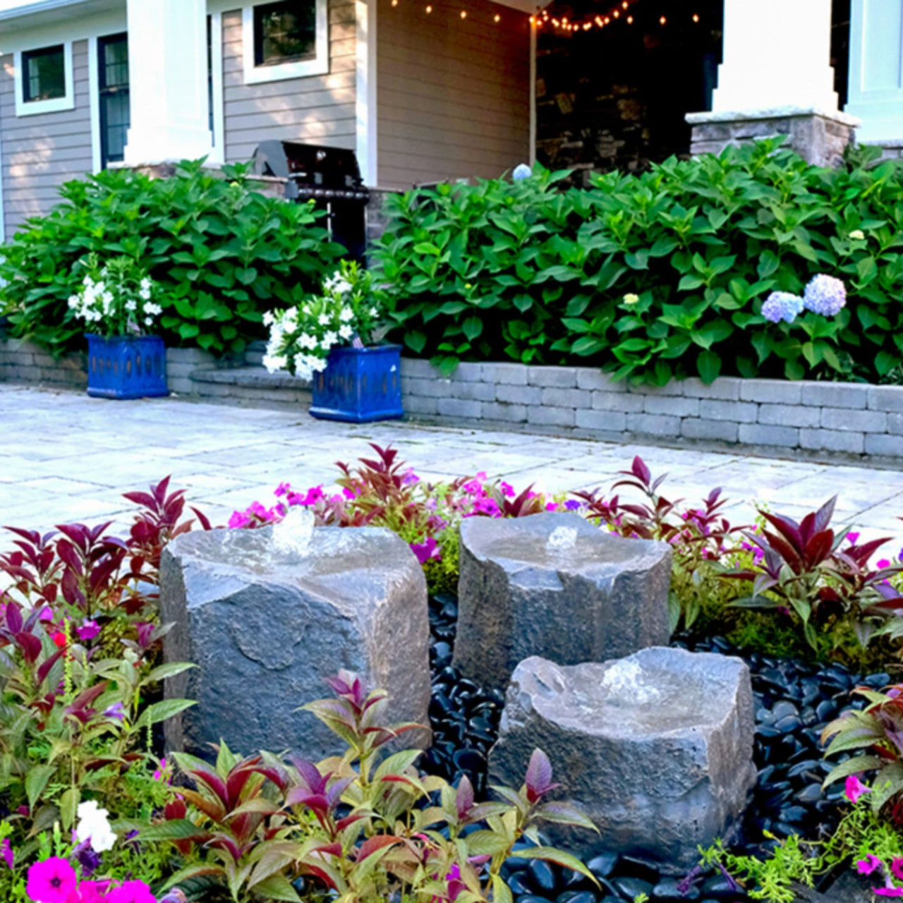 Blue Thumbs Triple Falls Garden Stone Fountain With Colorful Flowers And Green Bushes