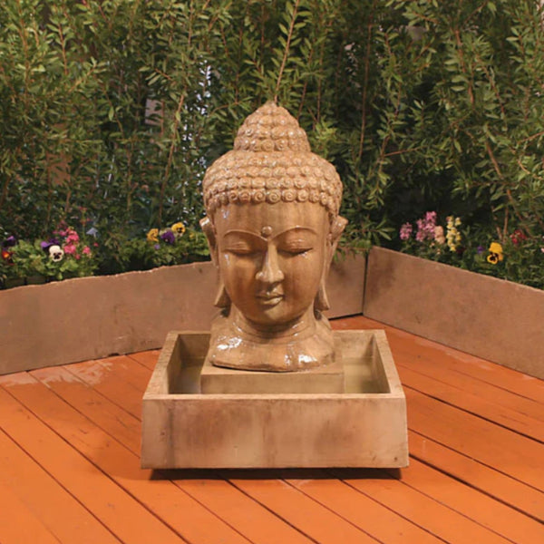 Buddha Head Water Fountain By Gist With Plants And Flowers In The Background