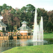 Cascade Orion Pond Fountain With Trees And Small Buildings  In The Background
