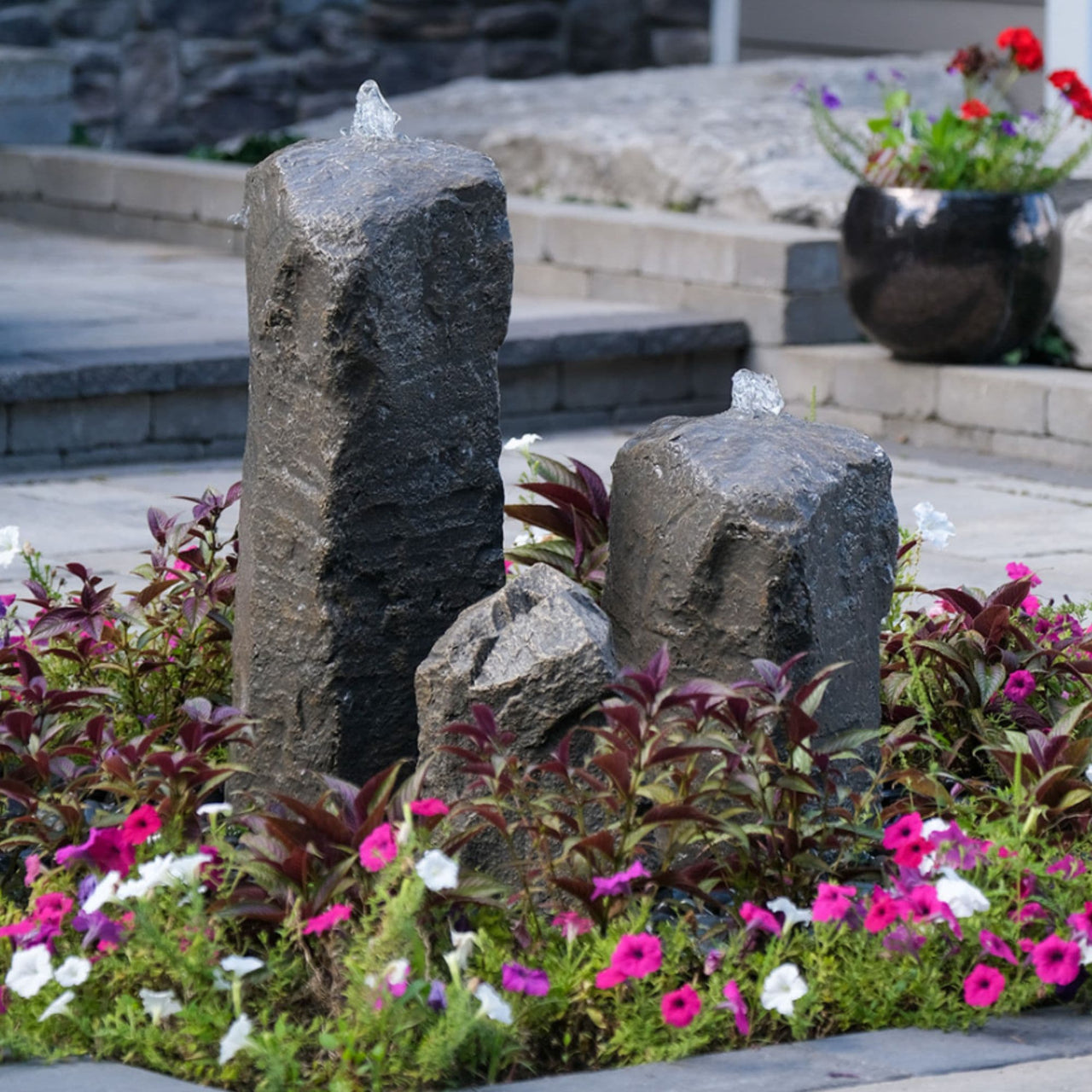 Double Cascade Stone Fountain with Accent Rock Surrounded By Flowers And Plants