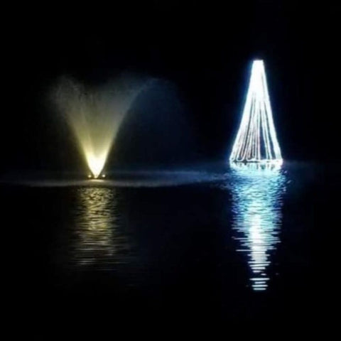 Floating Christmas Tree On The Water With White Lights & A Fountain Beside It