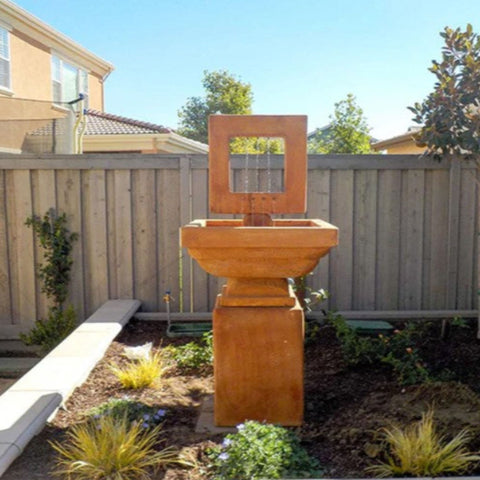 Giannini Contempo Square Fountain Tall For Bold Modern Entry Plazas With Wooden Fence And Tress In The Background