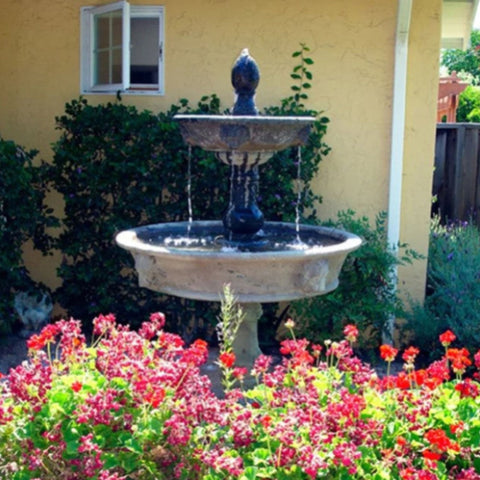 Giannini Garden Appia Antica Two Tier Lion Outdoor Water Fountain With Red Flowers In The front And A House In The Background