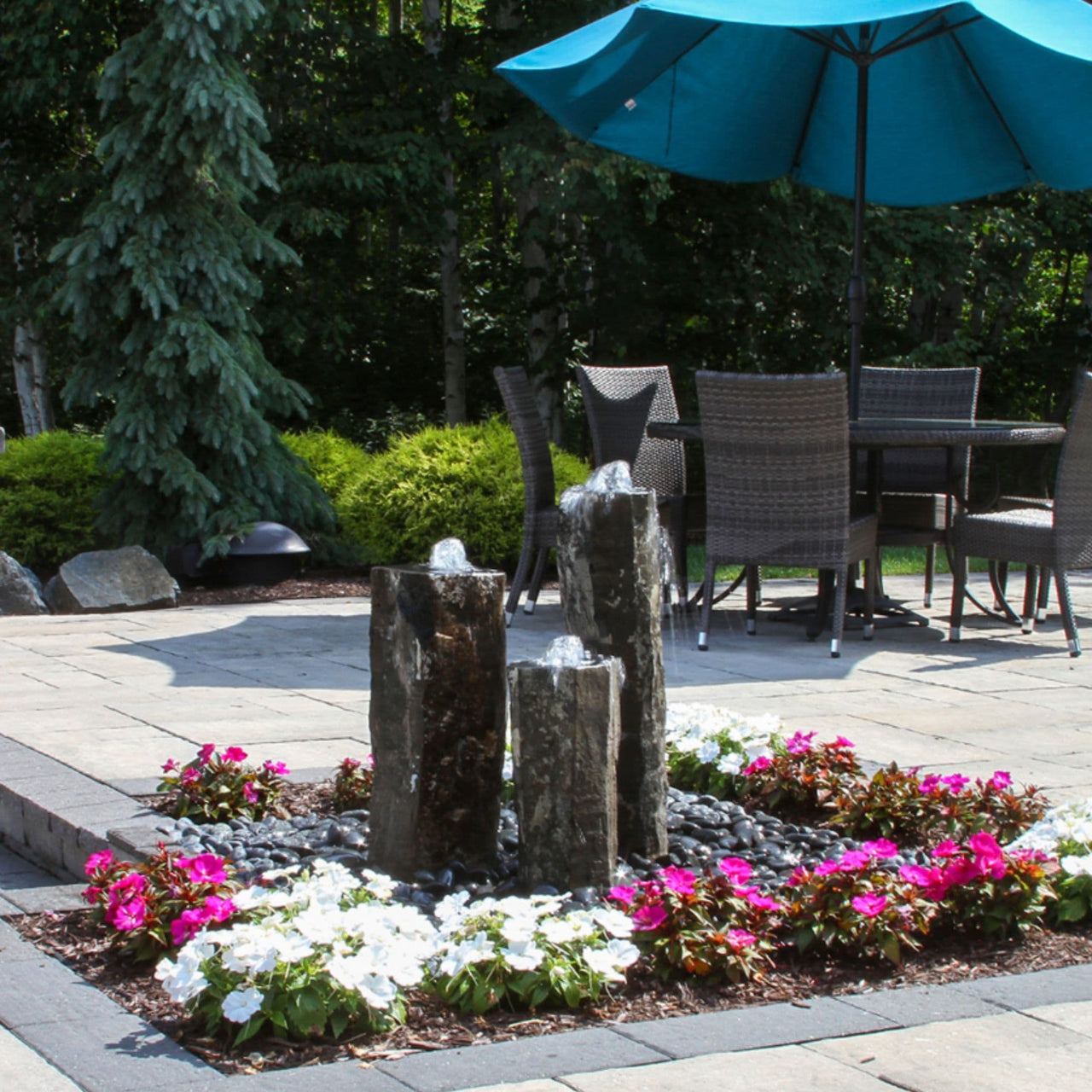 Hollowed-Out Basalt Column Outdoor Fountain On Outdoor Patio Seating With Blue Umbrella Shade