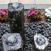 Hollowed-Out Basalt Column Outdoor Fountain Top View With Pink And White Flowers Behind