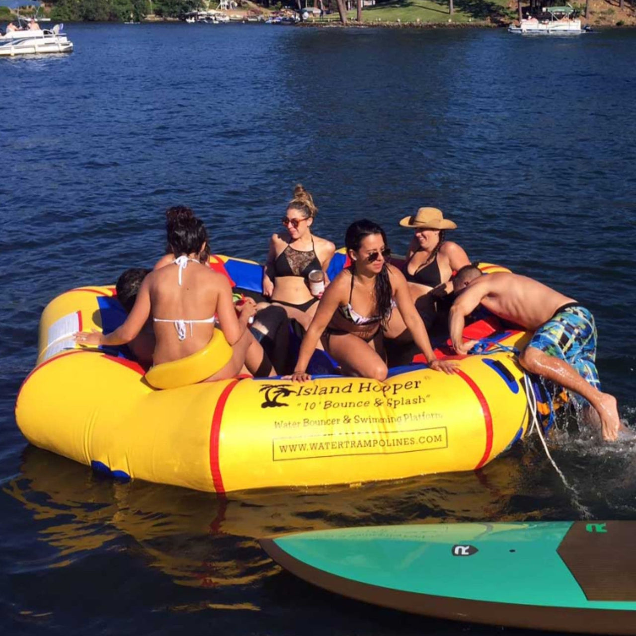 Island Hopper 10 Bounce and Splash Water Park w Slide Six People Having Fun On Trampoline With Paddleboard In Front