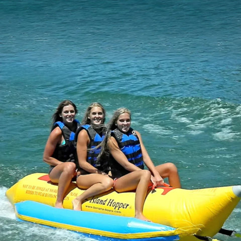 Island Hopper 3 Person Banana Boat  With Three Girls Smiling While Riding Waves