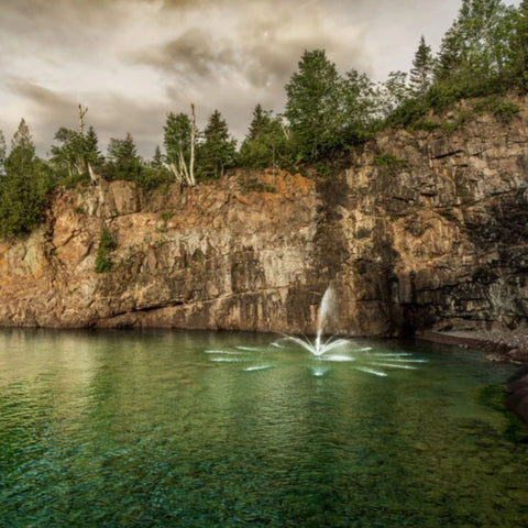 Kasco Marine Madrone Premium Fountain Nozzle Surrounded By A Rocky Cliff With Trees In The Background 