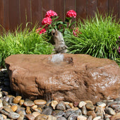 Large Bird Bath Boulder Stone Fountain Surrounded By Bright Ornamental Grass And Flowers And Wooden Fence