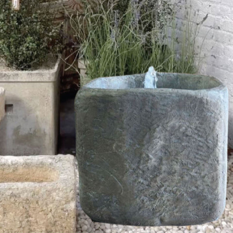 Limestone Bubbler Fountain With Grass And Plants In The Background