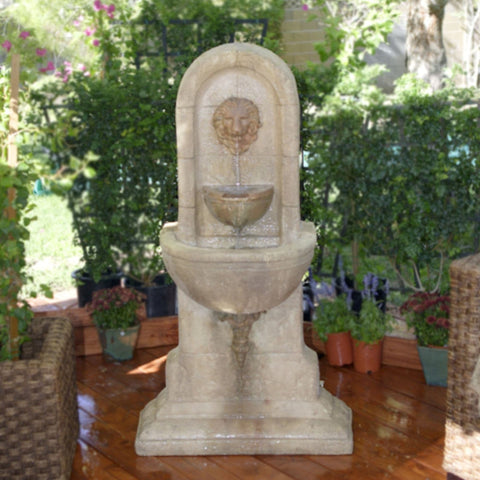 Lion Wall Water Fountain By Gist Besides A Rattan Planter And Plants In The Background