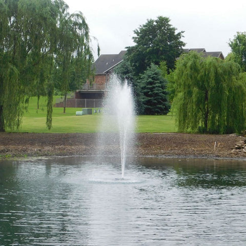 Outdoor Water Solutions EcoSeries Floating Pond Fountain With Equinox Spray Pattern On The Water With Trees & A House In The Background