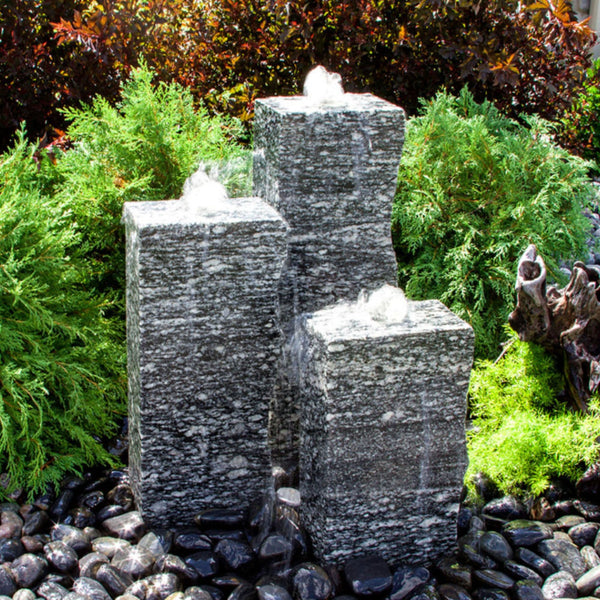 Outdoor Speckled Granite Fountain With Shrubs And Red Leaves Plants Behind
