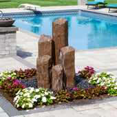 Pent 5 Column Stone Faux Basalt Fountain Color Chestnut Surrounded By Colorful Flowers With Pool In The Back