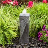 Thumbnail for Polished Twist Granite Stone Fountain Surrounded By Ferns, Plants And Vibrant Flowers